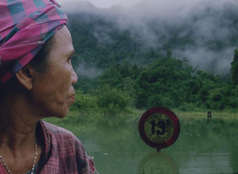 Une vieille femme vietnamienne se retourne et regard l'étendue d'eau et la végétation.
