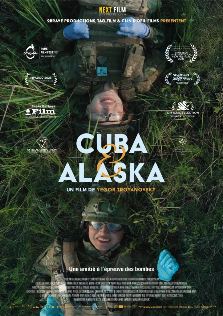 Affiche de Cuba et Alaska. Deux jeunes femmes en tenues militaires, allongées dans l'herbe, vues du dessus. Elles sourient. 